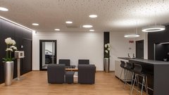 Ein modernes Wartezimmer mit eleganten Möbeln, einer Bar und stilvollen Orchideen in silbernen Vasen.