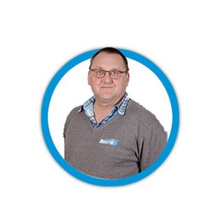 Ein Mann mit Brille trägt einen grauen Pullover und ein kariertes Hemd, lächelt freundlich in die Kamera.
