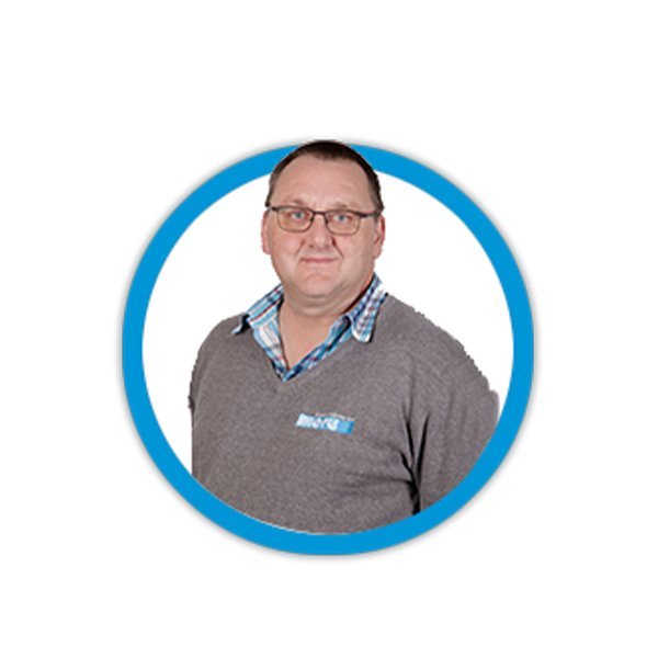 Ein Mann mit Brille trägt einen grauen Pullover und ein kariertes Hemd, lächelt freundlich in die Kamera.