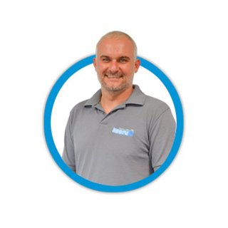 Ein lächelnder Mann mit grauem Poloshirt steht vor einem weißen Hintergrund, umgeben von einem blauen Kreis.