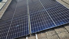 Eine Gruppe von Solarpanelen liegt auf einem Dach, die Sonnenstrahlen reflektieren sich auf den glänzenden Oberflächen.