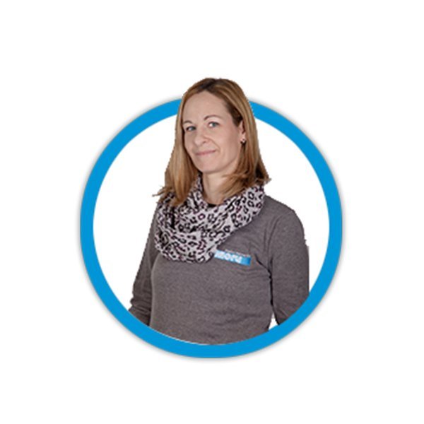 Eine lächelnde Frau mit blonden Haaren trägt einen gemusterten Schal und ein graues Oberteil, umgeben von einem blauen Kreis.