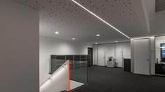 Ein modernes Büro mit einem eleganten Treppenaufgang, der von einer Glasbrüstung und einer roten LED-Leuchte beleuchtet wird.