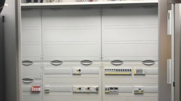 Die Wand ist mit einem Schaltkasten ausgestattet, der verschiedene elektrische Komponenten und farbige Kabel aufweist.