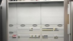Die Wand ist mit einem Schaltkasten ausgestattet, der verschiedene elektrische Komponenten und farbige Kabel aufweist.