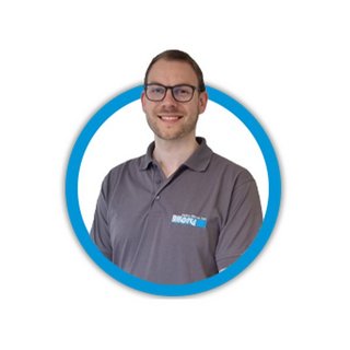 Ein lächelnder Mann trägt ein graues Poloshirt mit einem Logo, umgeben von einem blauen Kreis.