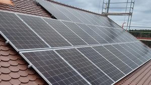 Auf einem braunen Dach sind mehrere Solarpanels installiert, die in einem modernen Design angeordnet sind.