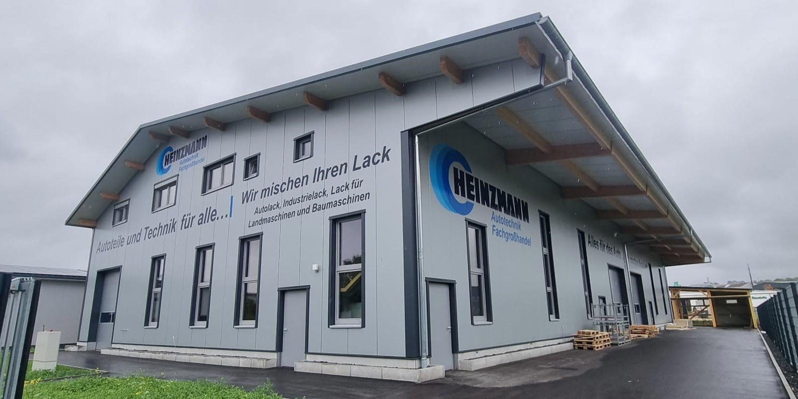 Ein modernes Gebäude mit grauer Fassade und großen Fenstern, das als Fachbetrieb für Autotechnik dient.
