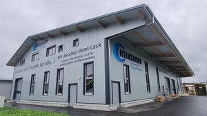 Ein modernes Gebäude mit grauer Fassade und großen Fenstern, das als Fachbetrieb für Autotechnik dient.