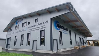 Ein modernes Gebäude mit grauer Fassade und großen Fenstern, das als Fachbetrieb für Autotechnik dient.
