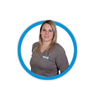 Eine lächelnde Frau mit langen, blonden Haaren trägt ein graues Oberteil und steht vor einem weißen Hintergrund.