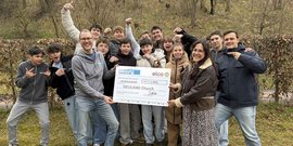 Eine Gruppe von Jugendlichen und Erwachsenen posiert fröhlich im Freien, während sie einen großen Scheck für die NEULAND Kirche halten.
